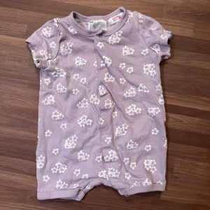 Ljuslila blommig romper - Söt ljuslila romper från H&M i storlek 62 (2-4mån). I fint skick utan anmärkningar.