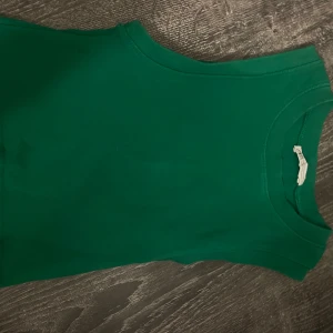Grön ärmlös topp från Zara - Snygg grön ärmlös topp från Zara i mjuk bomull. Enkel och stilren design med rund halsringning, perfekt att matcha med jeans eller kjol. Färgen är riktigt poppande grön och materialet känns skönt mot huden.