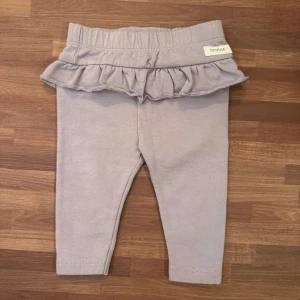 Ljuslila leggings med volang - Lila leggings med borstad insida från Newbie i storlek 68 (4-6mån). Använt fåtal gånger och är i extremt god skick utan anmärkningar.