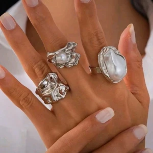 Silvriga statementringar med pärlor - Tre unika och chunky ringar i silverfärgad metall med organiska former. Två av ringarna har stora vita pärlor som ger en cool och modern vibe. Perfekt för dig som gillar att sticka ut med dina accessoarer.