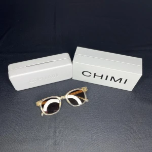 CHIMI solglasögon (02 ecru) - Snygga solglasögon från CHIMI med fyrkantig form och bruna tonade linser. Kommer med original ask, mjuk påse och putsduk. Ramen är i plast och har en modern vibe som passar dig som gillar stilrena solglasögon. Modellen är 02 ecru. Nypris=1400