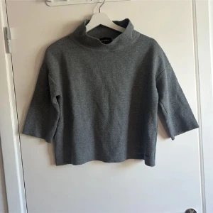 Grå polotröja från RefrigiWear - Säljer en stilren grå polotröja från RefrigiWear. Tröjan har en hög krage och trekvartsärmar, vilket ger en avslappnad men ändå trendig look. Perfekt för lager-på-lager och funkar året runt. Materialet känns mjukt och bekvämt mot huden.