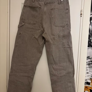 Grå cargopants från Zara, strl 44 - Säljer ett par grå cargopants från Zara i storlek 44. Byxorna har flera stora fickor, förstärkta partier på knäna och raka ben. Materialet är robust bomull och färgen är en neutral gråton som passar till det mesta. Perfekt för dig som gillar praktiska och snygga byxor. Knappt använda , nypris 1100kr