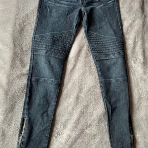 Svarta skinny jeans Michael Kors - Snygga svarta skinny jeans från Michael Kors med guldfärgade dragkedjor och detaljer. Byxorna har coola sömmar över knäna och dragkedjor vid bensluten. Materialet är bomull med stretch för skön passform. Perfekta för dig som gillar en edgy stil.