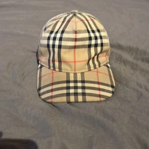 Burberry rutig keps beige L - Säljer dennna burberry keps köpt för 3500kr. Knappt använd och i väldigt bra skick. Säljer den billigt då den inte kommer till användning.