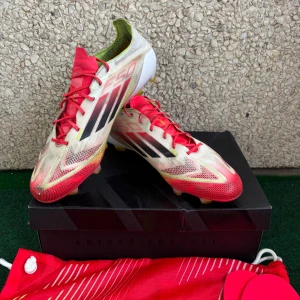 Adidas F50 fotbollsskor röd/vit - Säljer ett par Adidas F50 fotbollsskor i rött, vitt och svart med gula detaljer. Skorna har snörning, låg profil och är tillverkade i syntetmaterial för lätt känsla på planen. Medföljer originalpåse och extra innersulor. Perfekta för dig som vill sticka ut på fotbollsplanen. De går och spela med men bara att de behövs och limma på topen av den. Inget annan stans är de. De kommer med allt. 