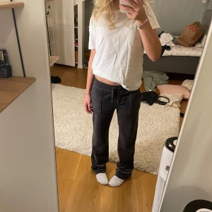 Mörkgrå mjukisbyxor Juicy Couture XS - Säljer ett par jättesnygga mörkgrå mjukisbyxor från Juicy Couture i storlek XS. Byxorna har snörning i midjan, raka ben och fickor med knappar där bak.