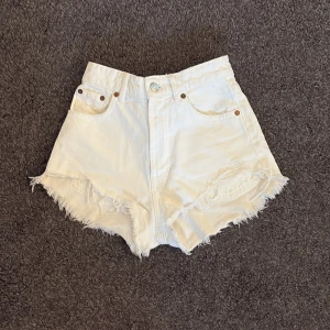 Vita högmidjade jeansshorts med fransar - Snygga vita jeansshorts som är hög midja, fransiga kanter. Klassisk femficksmodell med knapp och dragkedja framtill. 