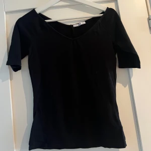 Svart v-ringad topp från Ellos - En svart, enkel topp från Ellos i storlek 34/36. Toppen har v-ringning och halvkorta ärmar, med en figurnära passform. 