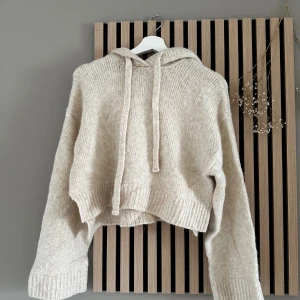 Beige stickad hoodie från Zara - Mysig beige stickad hoodie från Zara med croppad passform och breda ribbade muddar. Tröjan har huva med snörning och långa ärmar, perfekt för kyliga dagar. Enkel och stilren design som passar till många outfits. 💕