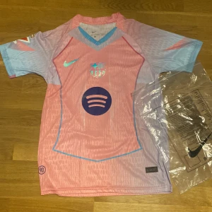Barça Lamine Yamal Nike fotbollströja - Använd en enstaka gång, annars helt ny. Säljer en FC Barcelona fotbollströja från Nike med Lamine Yamal och nummer 10 på ryggen. Tröjan är rosa och ljusblå med klubbmärke, Nike-logga och Spotify-sponsor på bröstet. Kortärmad modell i lätt funktionsmaterial, perfekt för match eller träning. Skicka dm vid frågor!
