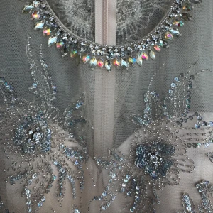 Champagnefärgad glittrig cocktailklänning - Superfin långklänning i champagnefärg med transparent mesh upptill och massor av glittrande paljetter och pärlor i blommigt mönster. Klänningen är ärmlös och har en snygg rundad halsringning med extra dekorationer. Perfekt för bal eller festligheter! Oanvänt endast provat. Köpt för 2500kr