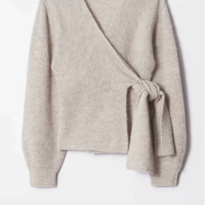 Beige omlottkofta i ullmix - Supermysig beige omlottkofta med knyt i sidan och v-ringning. Koftan är ribbstickad med långa ärmar och har en loose passform. Materialet är en mjuk ullmix som känns lyxig och varm.! Använt bara 2ggr är i nysskick SLUTSÅLD