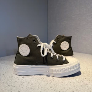 Converse Chuck Taylor All Star Platform - Converse Chuck Taylor All Star med vit hög platåsula och olivgrönt canvasmaterial. 