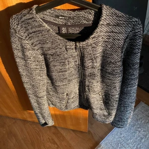 Grå stickad cardigan jacka Gina Tricot - Mysig gråmelerad stickad cardigan jacka från Gina Tricot i storlek M. Jackan har dragkedja framtill, två fickor med dragkedjor och rund halsringning. 