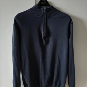 Mörkblå halvzip-tröja från Livergy - Mörkblå långärmad tröja från Livergy med ribbad hög krage och half zip-dragkedja framtill. Tröjan är i mjuk bomullsblandning och har en clean, stilren look som passar perfekt till jeans eller chinos.