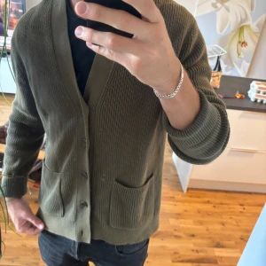 Olivgrön kofta från John Henric - Säljer en olivgrön ribbstickad kofta från John Henric. Perfekt för lager-på-lager stilen och nu inför hösten samt våren nästa år! Inga tecken på användning!