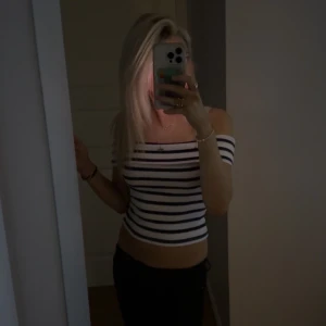 Randig offshoulder croppad topp - Säljer en snygg croppad topp med offshoulder-modell och marinblå och vita ränder. Toppen är figurnära och har korta ärmar. 