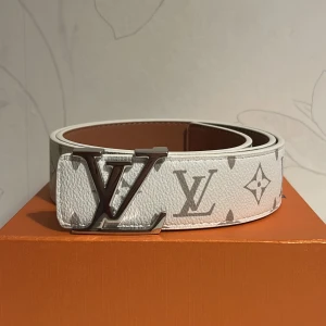 Bälte vit - Säljer ett snyggt bälte i vit med trendig blomdesign längs bältet och silver spänne. Bältet är i storlek 110. Allt på bilderna medföljer. 