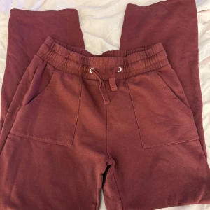 Vinröda mjukisbyxor från 157 - Mysiga vinröda mjukisbyxor från 157 med resår och snörning i midjan. Byxorna har två stora fickor framtill och är tillverkade i mjukt bomullsmaterial. Perfekta för chill dagar eller när du vill vara extra bekväm.