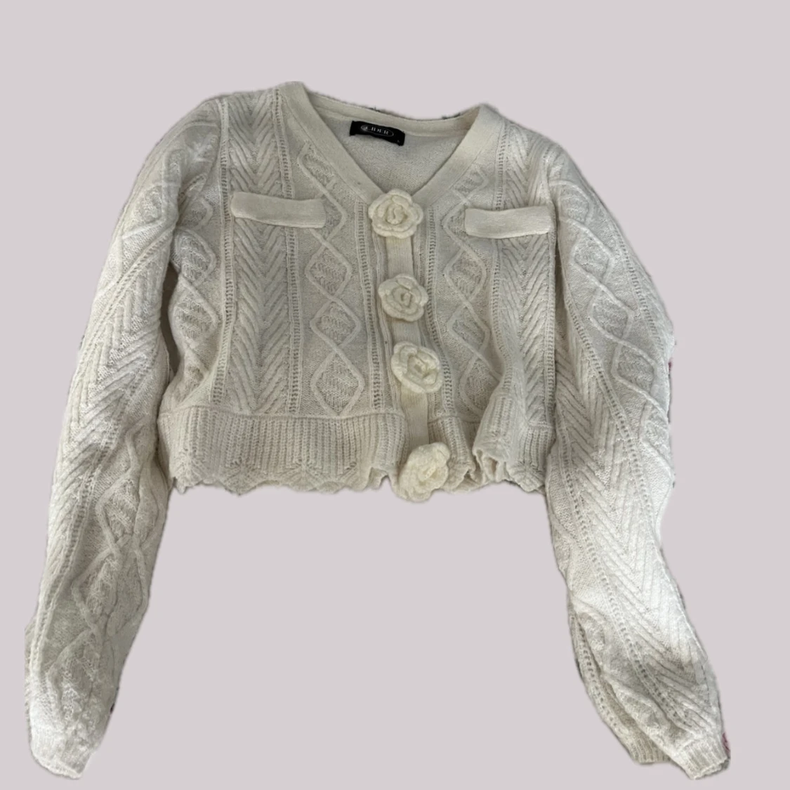 Vit stickad kofta med blommiga knappar