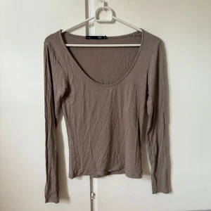 Beige långärmad topp från lager 157 - En basic beige långärmad topp från lager 157 med rund, djup ringning framtill. Tunn och mjuk i materialet, perfekt att styla med jeans eller kjol. Enkel och stilren design som funkar till många olika looks.
