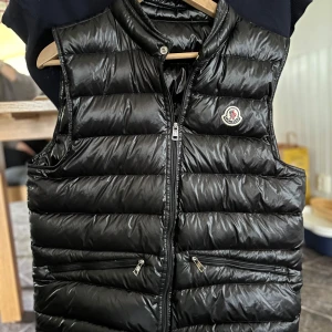 Moncler gui väst - Tjo, säljer nu min moncler väst då jag vill ha något annat. Qr kod funkar och även nfc scan. Finns en liten defekt på dragkedjan men inget som påverkar funktionen men även därav priset. Finns inga ytterligare defekter. Den är i storlek 2 vilket då motsvarar S. Den ser mycket glansigare ut på bilderna än vad den är. Inget og medföljer. Hör av dig vid frågor och funderingar/Emil
