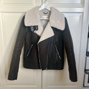 Olivgrön mockajacka med dragkedjor - Säljer en olivgrön jacka i imitationsmocka från hm. Den är olivgrön/brun beroende på ljus, går att stänga i kragen och är knappt använd!