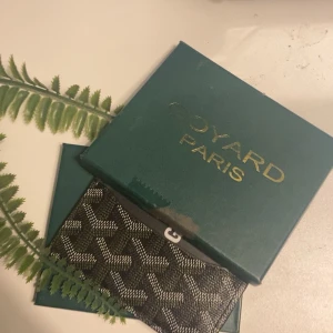 Svart plånbok med mönster - Snygg svart plånbok från med det klassiska grafiska mönstret i vitt och grått. Plånboken är tillverkad i skinn och har  Paris-loggan präglad på insidan. Perfekt för dig som gillar exklusiva accessoarer med unik design. Grisch, Laidback, avicci, soft , y2k