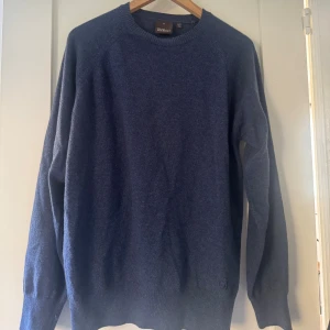 Mörkblå stickad tröja från Oscar jacobson - Mörkblå stickad tröja från Oscar jacobson med rund hals och långa ärmar. Tröjan är helt oanvänd och storlek S.