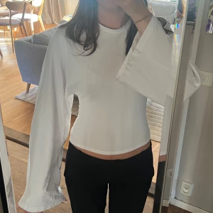 Vit lång ärmad tröja  - En vit tröja med vida ärmar och åtsittande midja ifrån Nelly. Stl - xxs. Bara andvänd en gång 