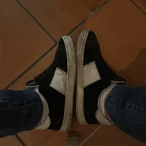 Valentino svartvita sneakers 41,5 - Säljer ett par Valentino sneakers i svart och vitt skinn med coola nitar på hälen. Klassisk rund tå, snörning och platt sula. Märkeslogga under sulan och på insidan. Riktigt snygga och stilrena skor som sticker ut med sina detaljer. Går och tvätta vid köp! Saknar 7 taggar.