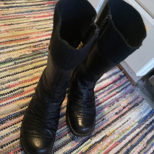 Snygga Fodrade Skinnstövlar Från Rieker Stl 39 - Stl 39, I finfin skick, svarta skinnstövlar med rund tå med snygga sömmar. Insidan är fodrad med mjukt vitt material som håller fötterna varma. Dragkedja på sidan gör dem enkla att ta på och av, rök och djurfri hem. Kan hämtas i Norra Stockholm. 