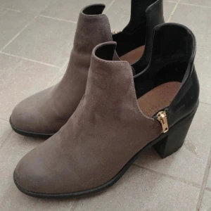 Grå mocka  stövletter strl 41 - Snygga stövletter från Zara med svart mocka framtill och svart skinn baktill. Mellanhög klack och guldfärgade dragkedjor på sidan. Använd vid ett tillfälle så är som nya. (Inte min storlek)