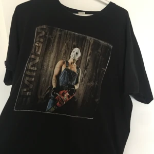 Eminem t-shirt - Cool svart t-shirt med stort tryck av Eminem i Jason-mask och overall, motorsåg i handen och trävägg i bakgrunden. Använd men i bra skick. (pris kan diskuteras)