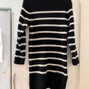 Randig svartvit stickad klänning H&M - Säljer en ribbstickad svartvit klänning från H&M i storlek L. Klänningen har horisontella vita ränder, lång ärm och är tillverkad av en mjuk blandning av polyester, akryl, ull och polyamid. Perfekt för dig som gillar en chill och stilren look.