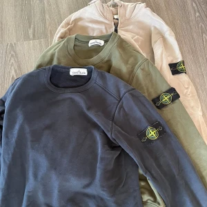 Svart Stone Island sweatshirt * 3  - Tre stycken Stone Island tröjor. En hoodie med dragkedja och två sweatshirts. Den två översta i mycket bra skick. Den svarta har ett litet hål, se bild. Säljer alla för 1200 el 500 styck för de två översta och 400 för den svarta. 
