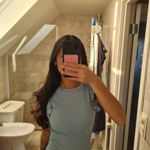 Ljusblå ribbad topp med volangärmar - Supersöt ljusblå topp med ribbad struktur och volangdetaljer på ärmarna. Modellen är ärmlös med rund halsringning och sitter snyggt slim på kroppen. Perfekt för dig som gillar en enkel men ändå lekfull stil. Materialet känns mjukt och stretchigt.