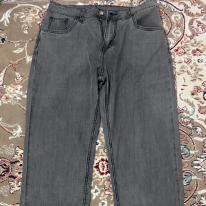 Grå raka jeansbyxor - Snygga grå jeansbyxor med klassisk femficksdesign och raka ben. Byxorna har normal passform och är tillverkade i ett mjukt jeanstyg som passar perfekt till en avslappnad stil. Stängs med knapp och dragkedja framtill.