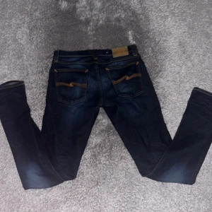 Mörkblå Nudie Jeans 28/34 skinny fit - Säljer ett par mörkblå skinny jeans från Nudie Jeans i storlek 28/34. Jeansen är väl omhändertagen och i fint skick, hör av er vid frågor eller annat!