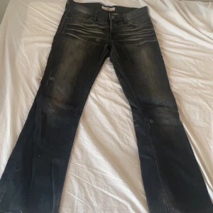 Svarta jeans från Fornarina bootcut - Snygga svarta jeans från Fornarina med bootcut-modell och slitningar framtill. Jeansen har klassisk femficksdesign, dragkedja och knapp i midjan samt coola detaljer vid fickorna. Perfekta för dig som gillar en avslappnad men trendig look.