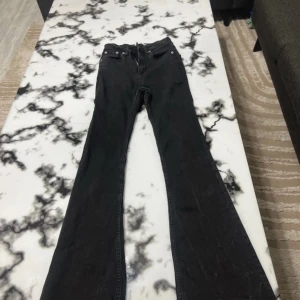 Svarta bootcut jeans - Svarta jeans med klassisk femficksdesign och bootcut-ben. Jeansen har normal midja och är tillverkade i ett mjukt denimtyg som ger en skön passform. Perfekta för dig som gillar en retroinspirerad look med utsvängda ben.