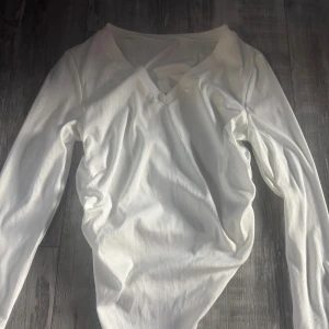 Vit v ringad ribbad långärmad topp Shein -  Toppen har en asymmetrisk nederkant som ger en cool och modern look. Materialet är mjukt och stretchigt, perfekt att styla med jeans eller kjol. 