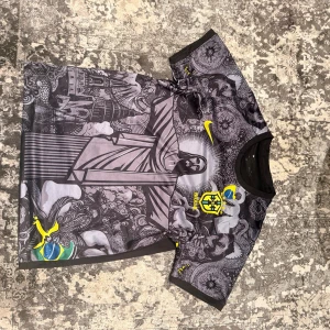  fotbollströja - Unik svart och grå Brasilien fotbollströja från Nike med detaljerat grafiskt mönster som inkluderar Kristusstatyn och brasilianska symboler. Kortärmad modell med gul Nike-logga och Brasilien-emblem på bröstet. Perfekt för dig som vill sticka ut på planen.