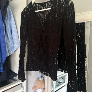 Svart spetsblus med snörning Gina Tricot - Säljer en svart långärmad blus från Gina Tricot i storlek XS. Blusen är helt i spets med snygg snörning framtill och v-ringad hals. Den har en slim passform och är perfekt för dig som gillar detaljer och transparent look.