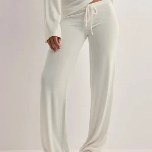 Vita mjukisbyxor med snörning - Säljer ett par vita mjukisbyxor med dragsko i midjan. Byxorna har en loose passform och raka ben, perfekta för en chill och avslappnad stil. Tillverkade i mjukt material som känns skönt mot huden.