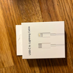 USB-C to Lightning Cable - Apple USB-C till Lightning-kabel, perfekt för laddning och synkronisering av iPhone, iPad och andra Apple-enheter. Produkten är i originalförpackning och ser oanvänd ut. Passar utmärkt för snabbladdning och dataöverföring.