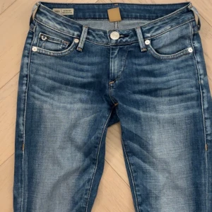True Religion Joey Low Rise Flare Jeans - Snygga blå jeans från True Religion, modell Joey med låg midja och utsvängda ben. Väldigt fina fickor baktill med fina detaljer och knappar. De går inte längre att köpa i butik. Väldigt bra material, ganska stretchiga i benen. Det är storlek 24, modell joey.