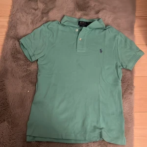  pikétröja från Ralph Lauren - Snygg pikétröja från Polo Ralph Lauren i slim fit-modell. Klassisk krage, korta ärmar och två knappar framtill. Ikoniska broderade logganpå bröstet. Perfekt för en fräsch och stilren look, väldigt sällan använt, ny pris 1000kr