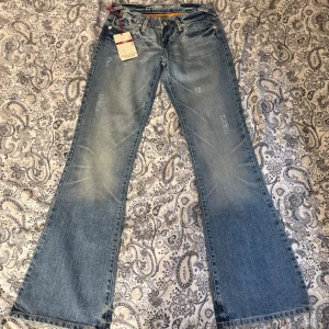 Lågmidjade utsvängda jeans  - Lågmidjade utsvängda jeans  Midjemått rakt över: 37cm Innerbenslängd: 81cm Total längd: 102cm Benvidd nedtill: 25cm
